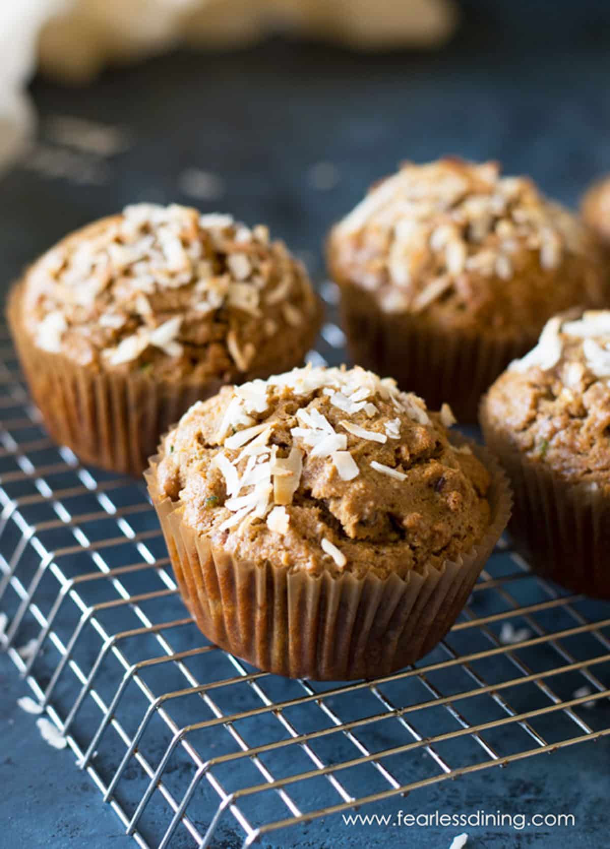 Four zucchini muffins on a wire rack.