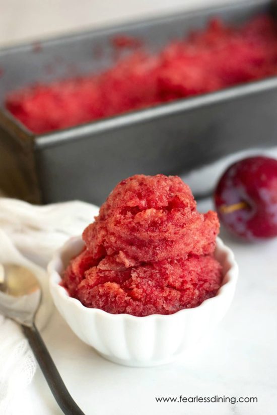 A small bowl of frozen plum sorbet. It is next to the sorbet container.