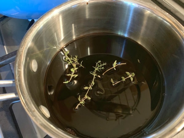 Balsamic vinegar in a pan with fresh herbs.