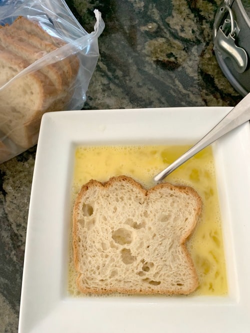 a slice of bread in a bowl of egg mixture 
