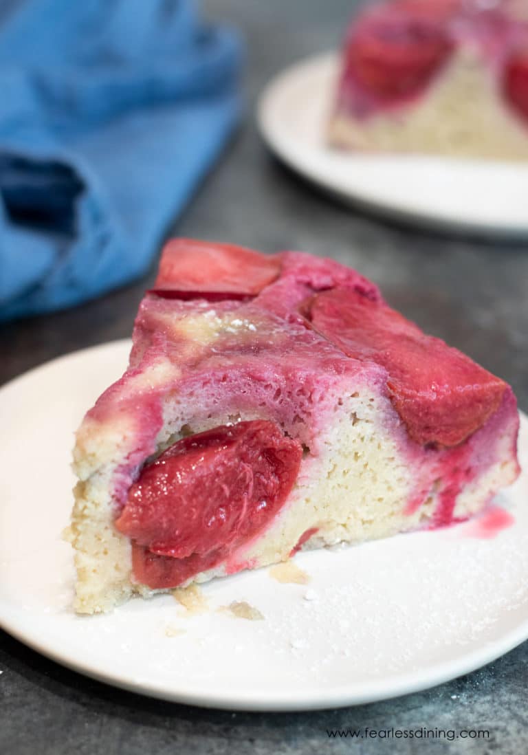 A slice of plum upside down cake on a small white plate.
