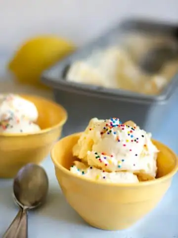 a yellow bowl filled with lemon ice cream. It is topped with rainbow sprinkles