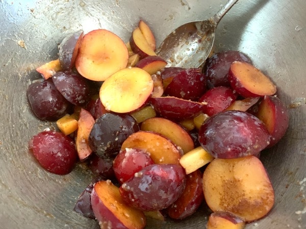 The chopped plums in a silver mixing bowl.