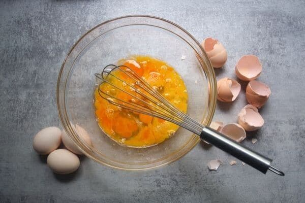raw eggs with a whisk in a bowl