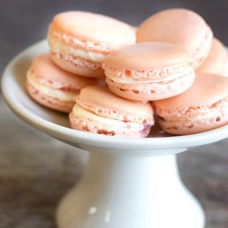 A white serving dish filled with raspberry macarons.