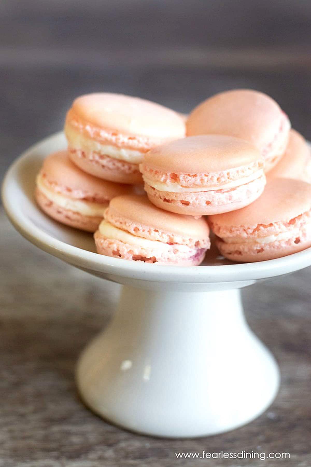 A white platter filled with raspberry macarons.