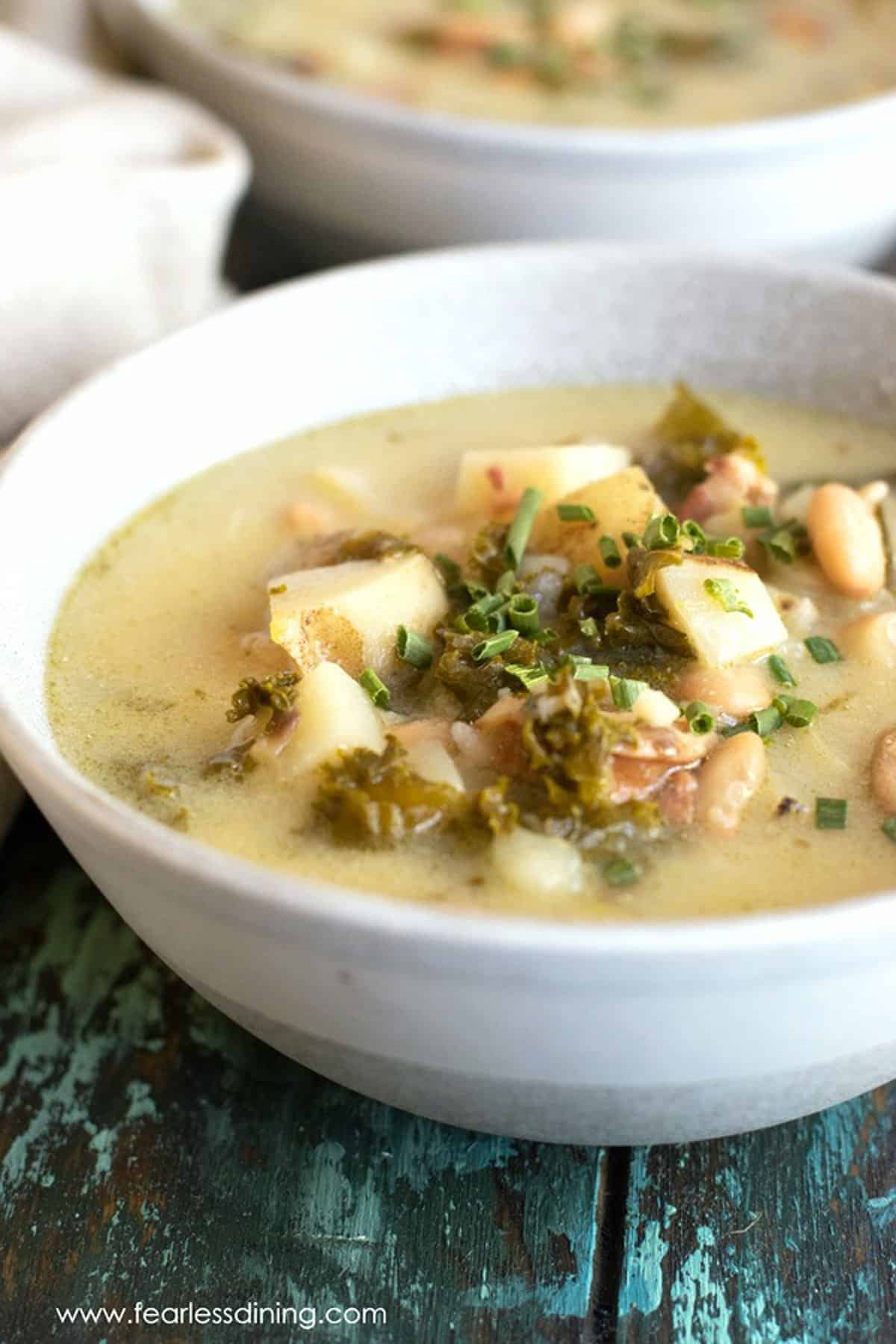 Two bowls of slow cooker zuppa potato kale soup on a table.