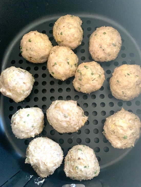 Cooked ground chicken meatballs in an air fryer basket.