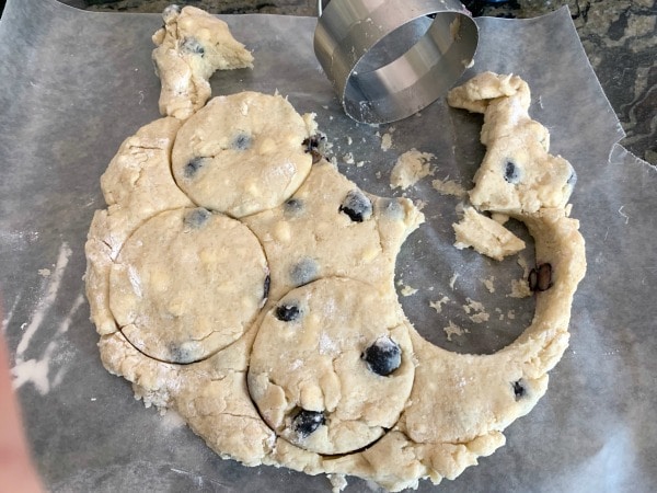 Using a biscuit cutter to cut out round scones.