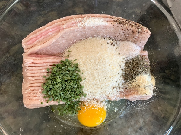 Raw ground chicken and ingredients in a bowl.