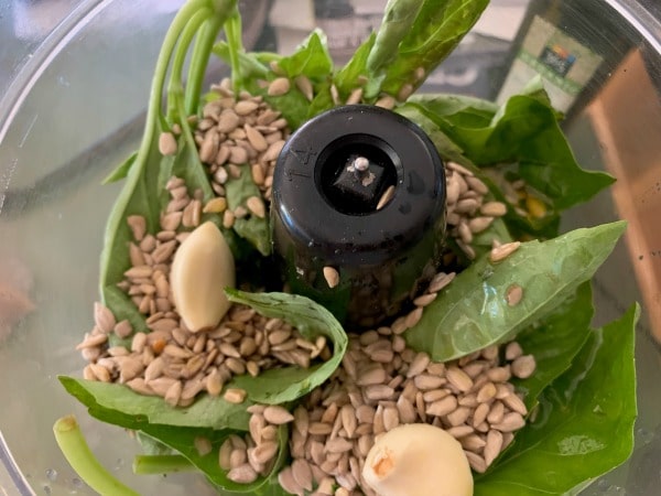 Fresh basil, garlic, sesame seeds in a food processor.