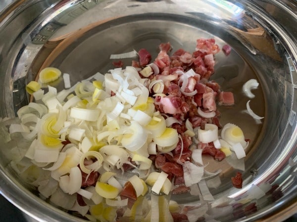 Leeks and pancetta cooking in a skillet.