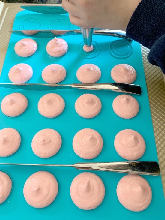 Filling all of the circles with macaron batter.