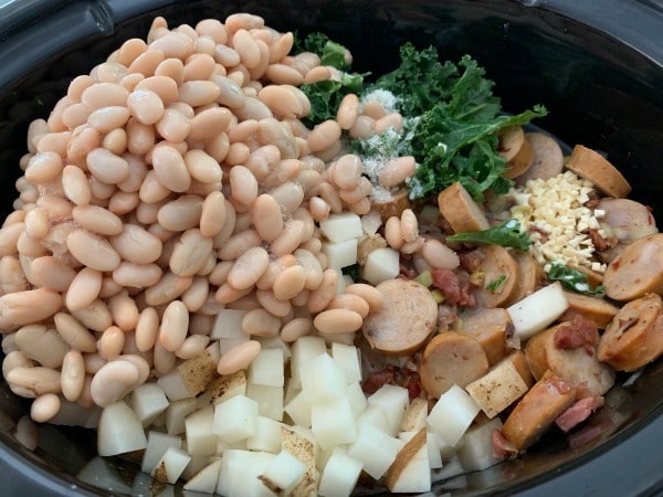 Adding the beans and other ingredients to the slow cooker.