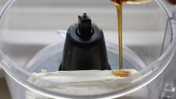 Adding cream cheese and maple syrup in a food processor.