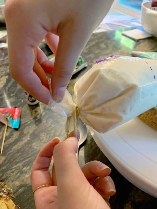 Tying off the end of the frosting bag with a rubber band.
