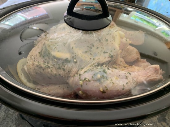 A seasoned raw chicken in a slow cooker.