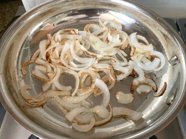 Sliced onions caramelizing in a pan.
