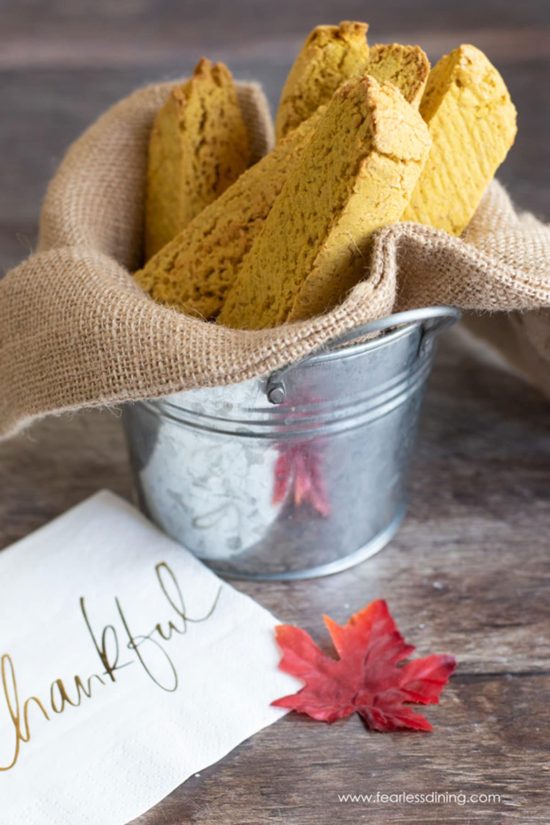 A small metal pail filled with gluten free pumpkin biscotti.