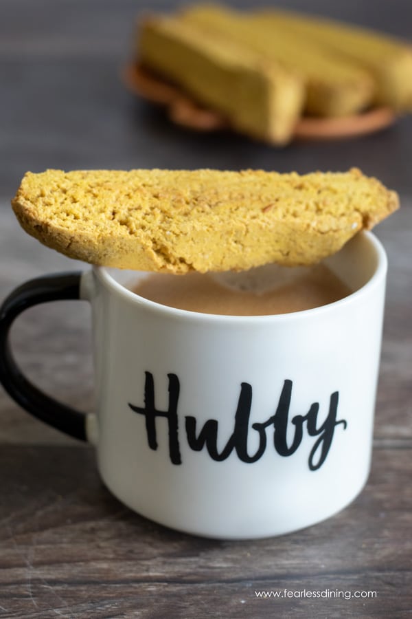 A piece of pumpkin biscotti on a coffee mug.