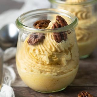 Two jars of pumpkin mousse topped with candied pecans.