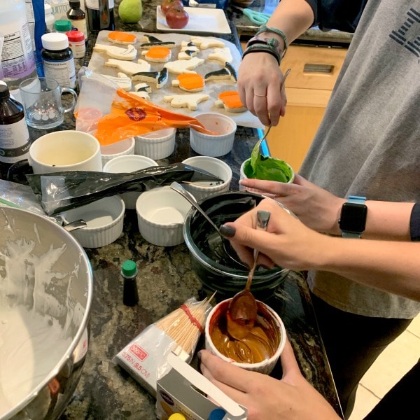 Adding food color to small jars of the royal icing.