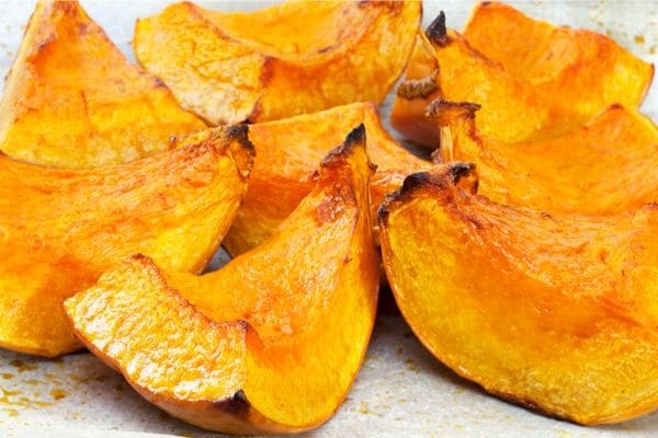 Roasted pumpkin wedges on a baking sheet.