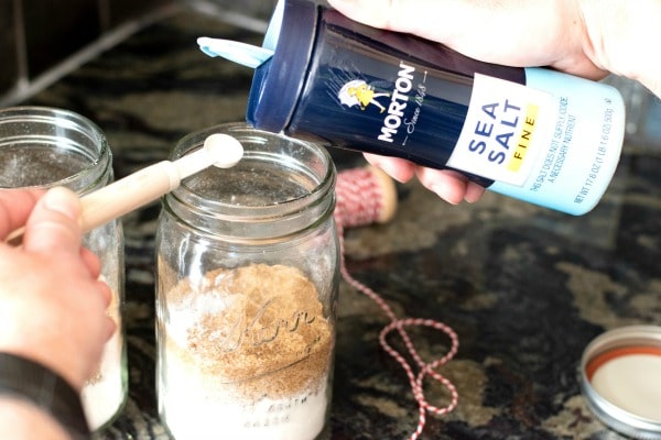 Pouring Morton Sea Salt into a measuring spoon.