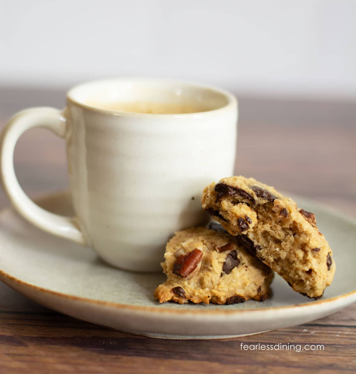 A cup of espresso with a cookie cut in half on the saucer.