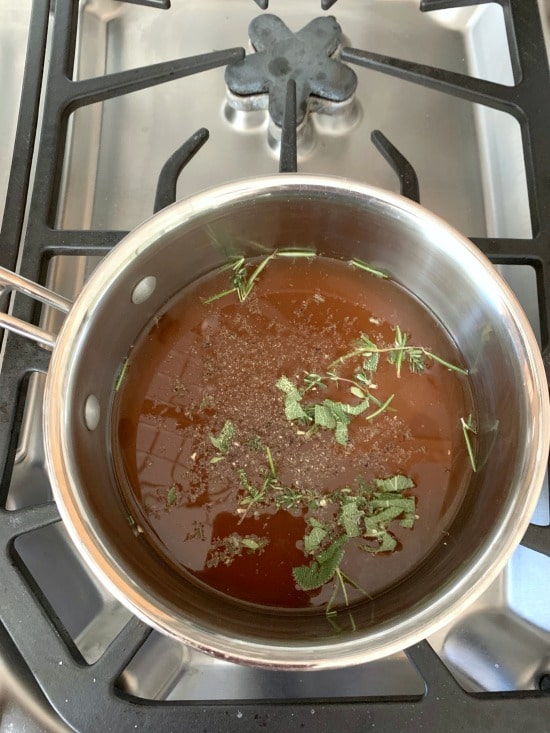 Gravy and fresh herbs simmering on the stove.