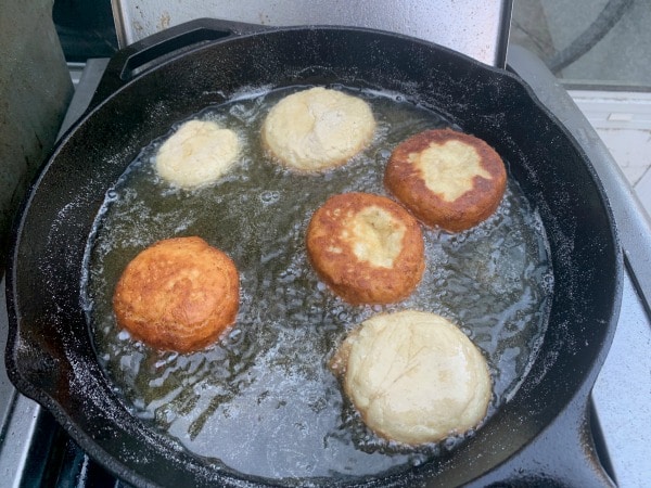 Frying the gluten free jelly donuts in hot oil in a cast iron skillet.