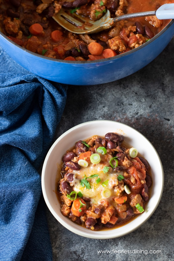 The top view of a bowl of chili next to the pot full of chili.