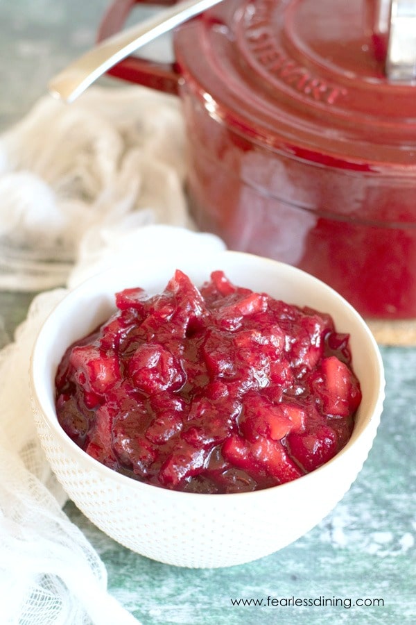 A bowl of cranberry sauce next to a red pot.