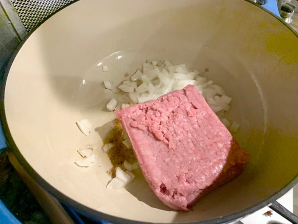 Browning ground pork, oil, and onion in a Dutch oven.