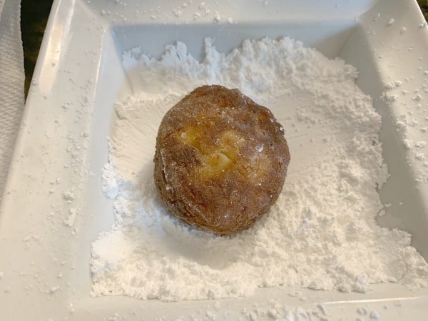 rolling sufganiyot in powdered sugar