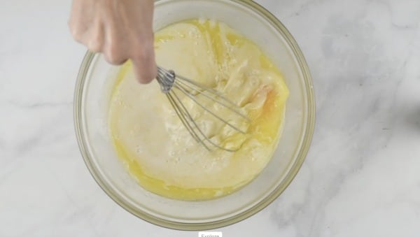Whisking the wet ingredients in a glass mixing bowl.