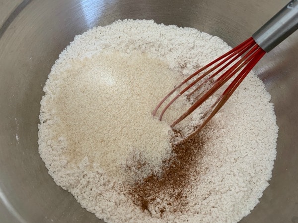 The apple muffin dry ingredients in a mixing bowl with a red whisk.