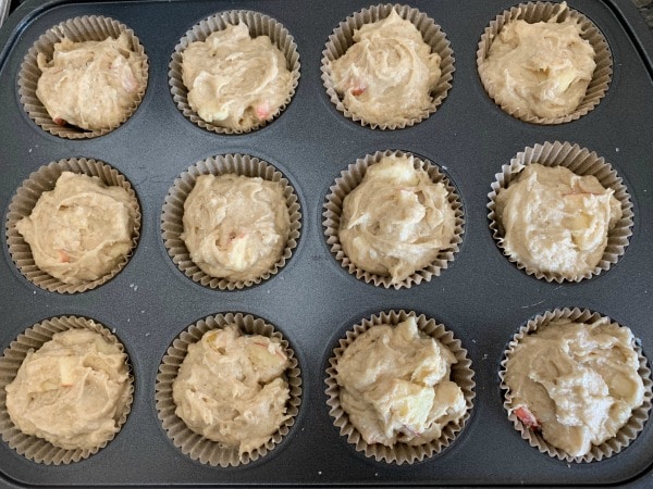 Apple muffin batter in a muffin tin ready to bake.