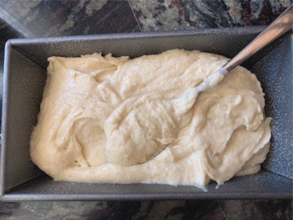 Spreading lemon pound cake batter in a loaf tin.