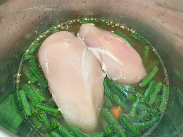 adding chicken and broth to the Instant Pot
