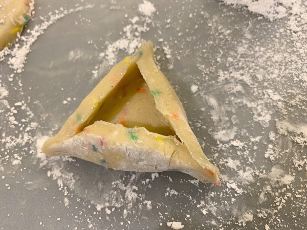Shaping the hamantaschen into triangles.