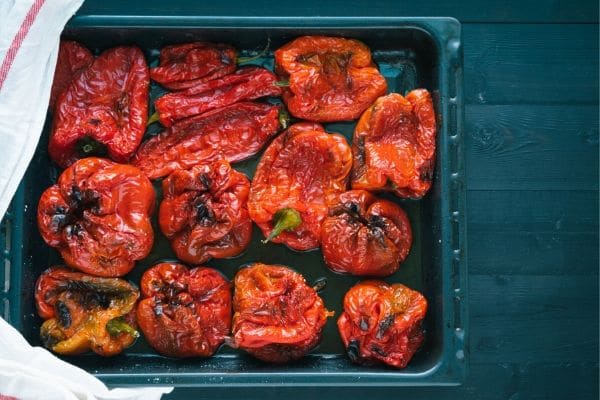 Fire roasted red peppers on a grill basket.