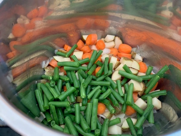 Adding the chopped vegetables to the Instant Pot.