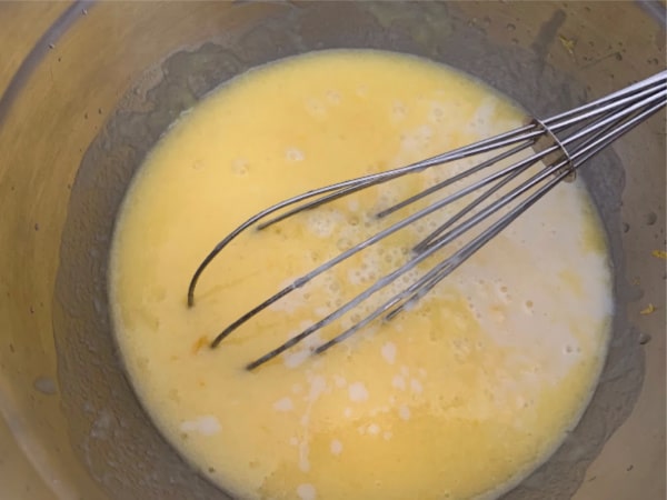 A bowl with the wet lemon madeleine ingredients.