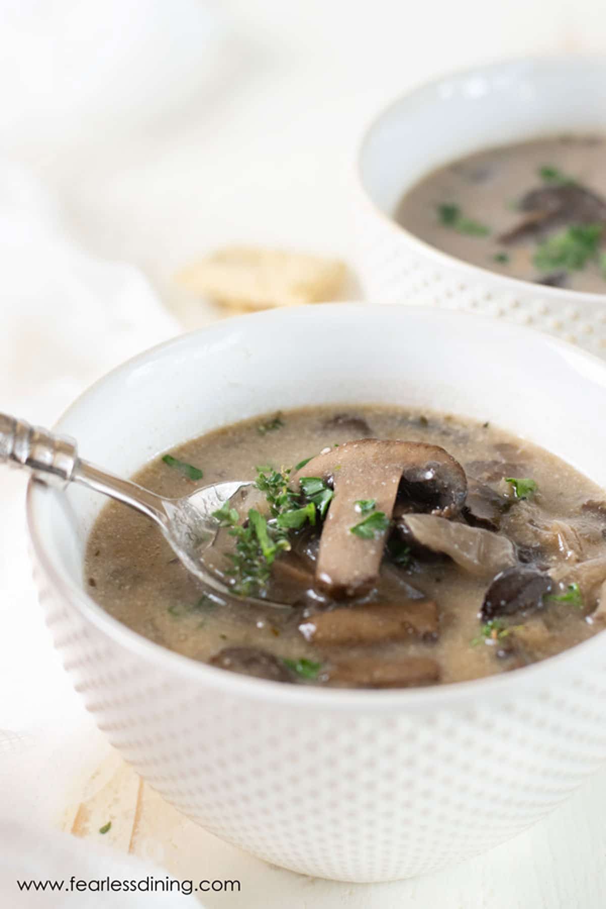 A spoon holding up a spoonful of gluten free mushroom soup.