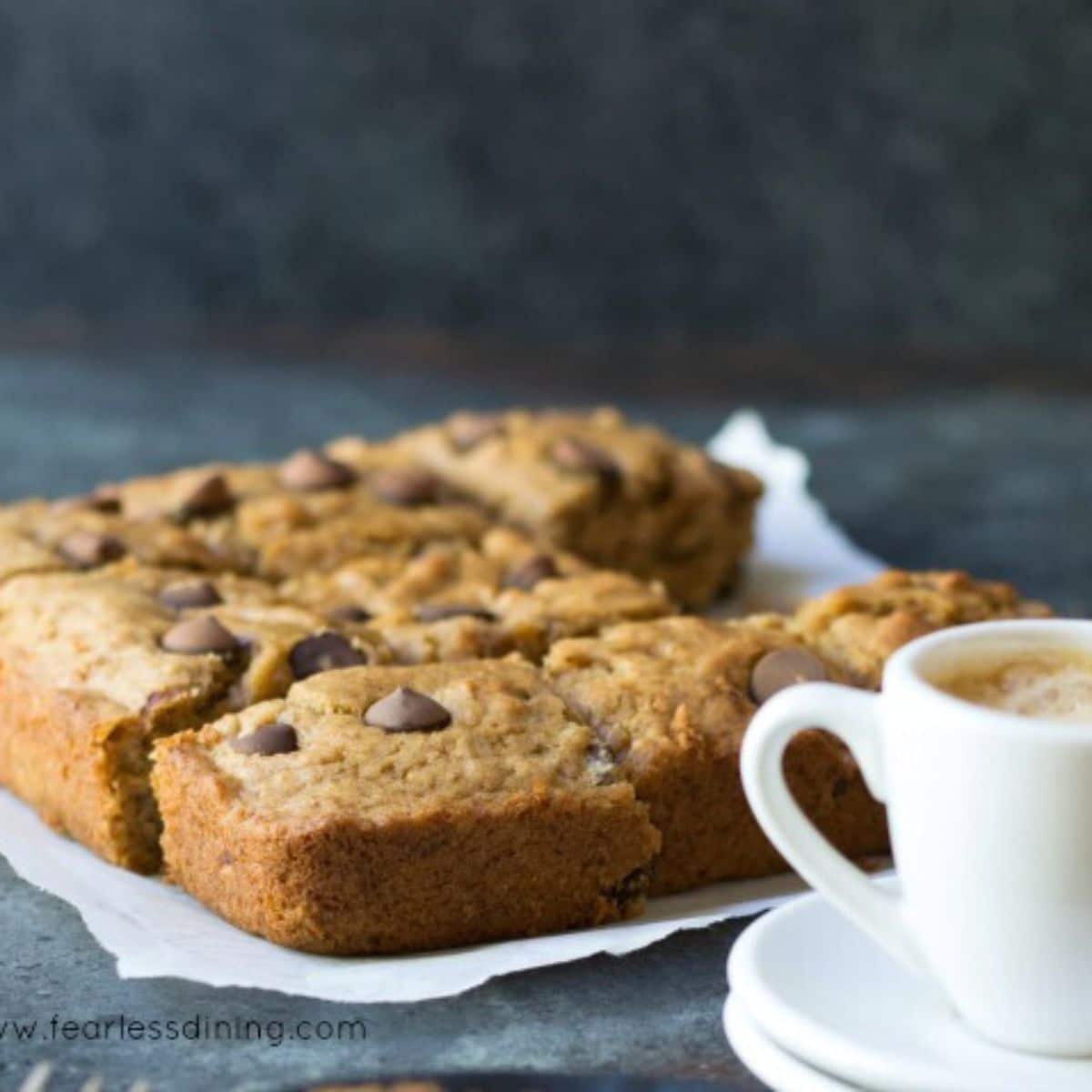 Baked banana bars next to a cup of espresso.