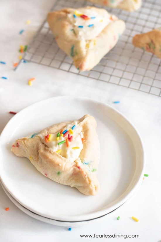 A gluten-free funfetti hamantaschen cookie on a small white plate.