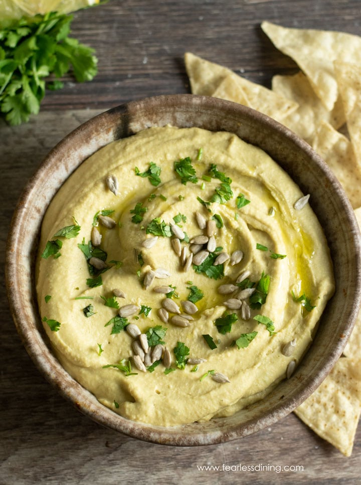 The top view of a pottery bowl filled with avocado salsa hummus. Corn chips are all around the bowl.