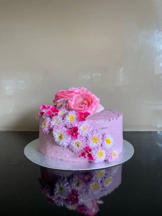 Leah W sent a photo of this cake with pink frosting and decorated with fresh pin and purple flowers.