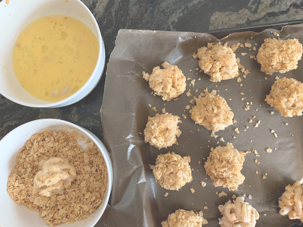 crushed crackers in one bowl, egg in another and some mac and cheese bites getting coated
